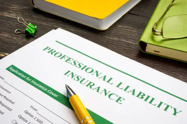 Photo of Professional liability insurance and yellow pen for signing.