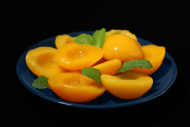 istock Plate with canned peach halves on black background 1326064125