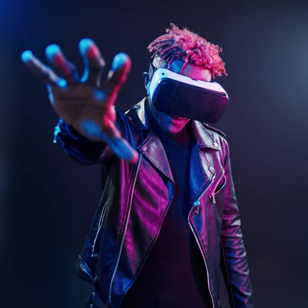 Virtual reality experience. Futuristic neon lighting. Young african american man in the studio