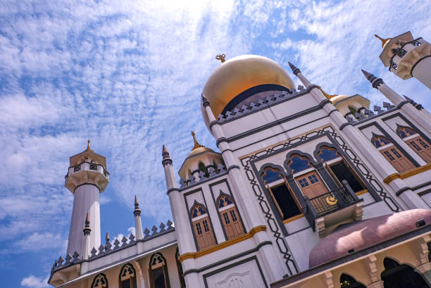 prospettiva dinamica, vista a bassa angolazione dell'edificio islamico sultan mosque o masjid sultan contro il soleggiato cielo blu brillante con nuvole, singapore kampong glam - gold dome foto e immagini stock