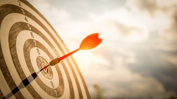 ダークブルーの空の背景にダーツボードセンターのターゲットにショット赤ダーツの矢印をクローズアップ。ビジネス目標または目標の成功と勝者の概念。 - dartboard ストックフォトと画像