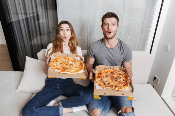 istock Excited young couple holding boxes with pizza 1326070323