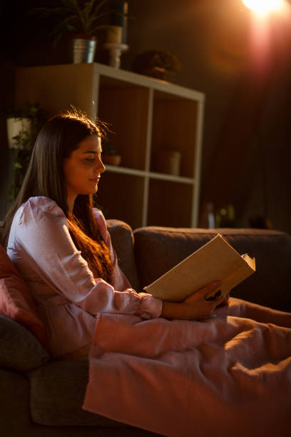 istock Young woman relaxing on the sofa and reading a book 1326071270