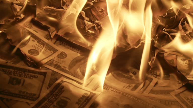 many Hundred dollar bills scattered on the floor are burned, close-up. Lot of hundreddollar bills are burning on the floor. Concept of inflation