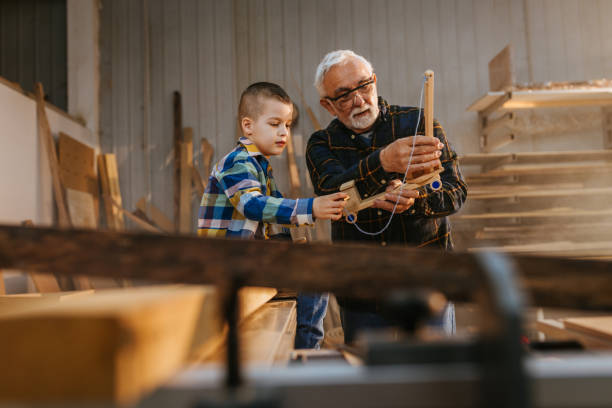 istock Little boy is playing with grandfather in his workshop 1326071558
