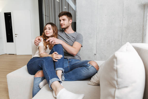 istock Happy young couple hugging while sitting together on a couch 1326071924