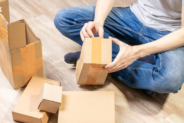 istock male person indoors unpack cardboard parcel package. men opening box. delivery service concept. online shopping conceptual 1326072721