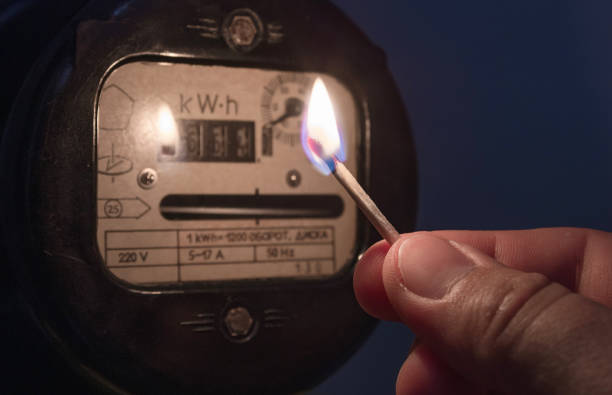 istock Hand in complete darkness holds a burning matchstick to reading a home electricity meter. Blackout, energy crisis or power outage, concept image. 1326073686