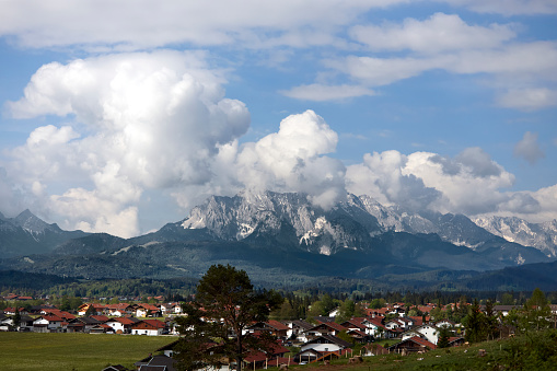 Full frame daylight suburb overview image with spectacular clouds above a high peak mountain in Germany