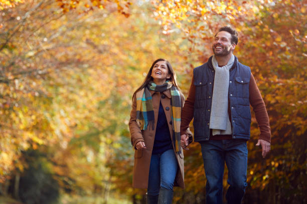 pareja madura amorosa cogiendo de la mano caminando por la pista en el campo de otoño - couple love autumn romance fotografías e imágenes de stock