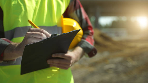 Builder with hard hat inspects construction site. Close-up. stock photo