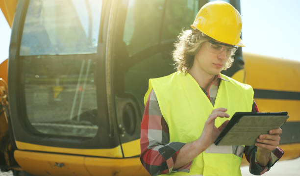 опе�ратор экскаватора в твердой шляпе с помощью планшетного пк. - foreman road construction manual worker manager стоковые фото и изображения