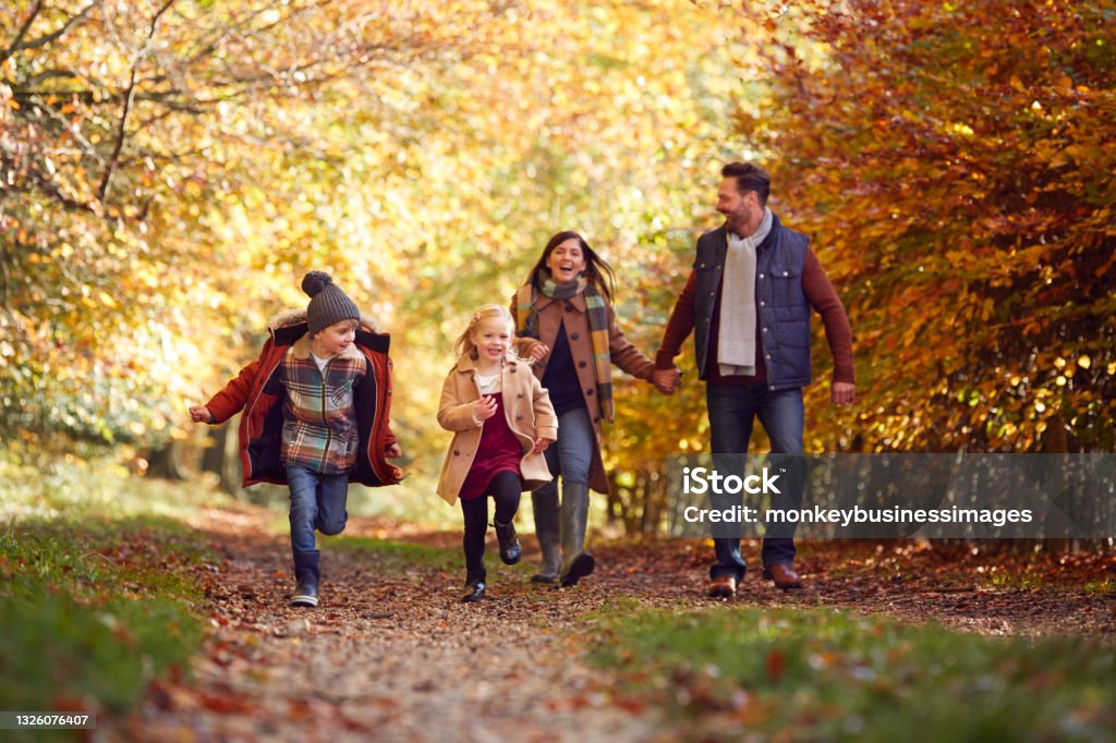Family Walking Along Track In Autumn Countryside With Children Running Ahead Family Stock Photo
