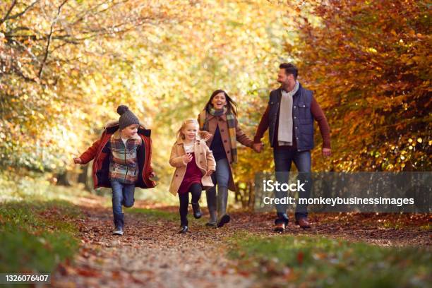 Family Walking Along Track In Autumn Countryside With Children Running Ahead Stock Photo - Download Image Now