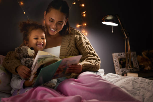 strzał młodej matki czytając jej córka na dobranoc - child reading mother book zdjęcia i obrazy z banku zdjęć
