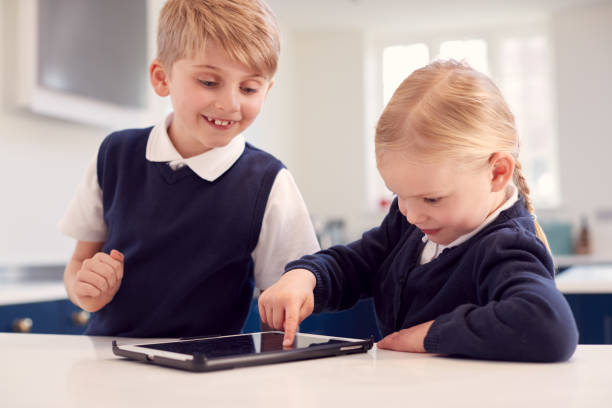 istock Children Wearing School Uniform In Kitchen Playing With Digital Tablet On Counter 1326079072