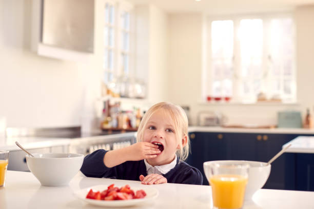 istock Girl Wearing School Uniform In Kitchen Taking Fresh Strawberries For Breakfast From Counter 1326079331