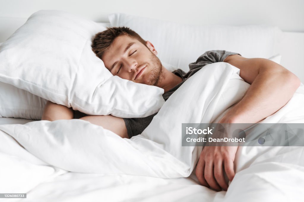 Handsome young man sleeping in bed Handsome young man sleeping in bed at home Sleeping Stock Photo