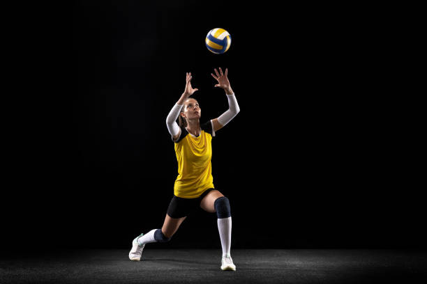 Female professional volleyball player with ball isolated on black studio background. The athlete, exercise, action, sport, healthy lifestyle, training, fitness concept. Female professional passer volleyball player with ball isolated on black studio background. The athlete, exercise, sport, healthy lifestyle, training, fitness concept. The girl in motion in striker kick the black ball stock pictures, royalty-free photos & images