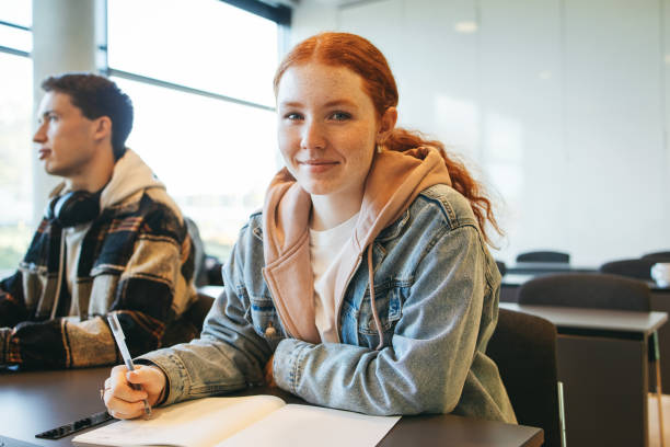 junge frau sitzt in ihrem klassenzimmer - highschool student stock-fotos und bilder