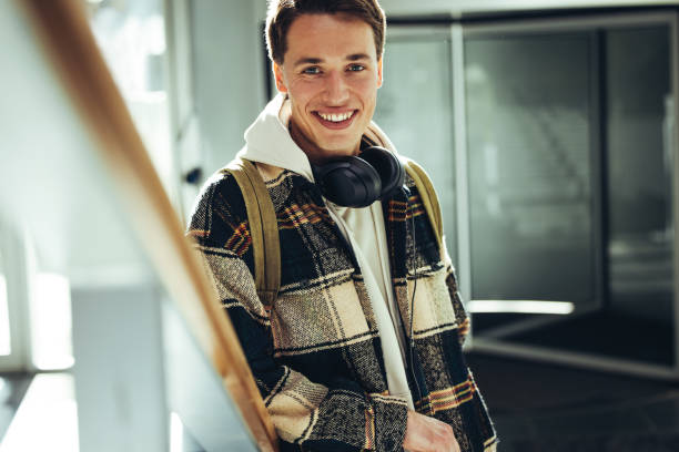 istock Young man smiling at camera at college staircase 1326084036