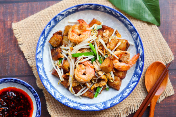 Stir fried turnip cake with shrimp, bean spout and chives - Thai -Chinese food called Kanom Pak kad or Char Koay Kak Chinese food at top view with chili dipping sauce cantonese cuisine stock pictures, royalty-free photos & images