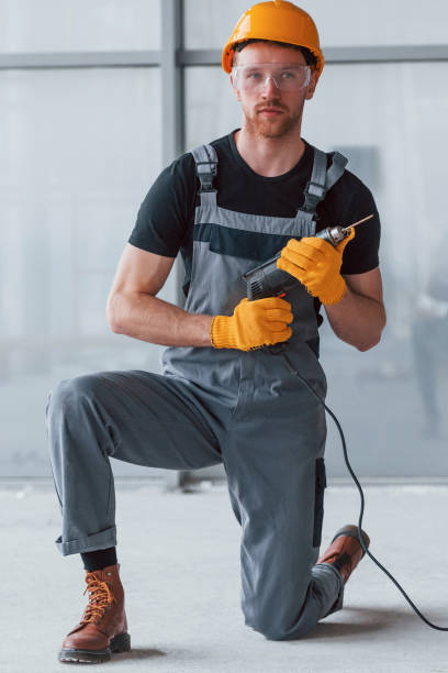 istock Man in grey uniform with drill in hand standing indoors in modern big office at daytime 1326086697