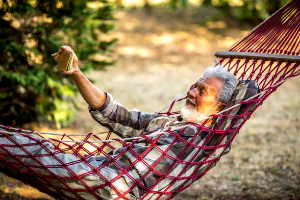 istock Senior Man Lying In Hammock Taking Picture 1326087517