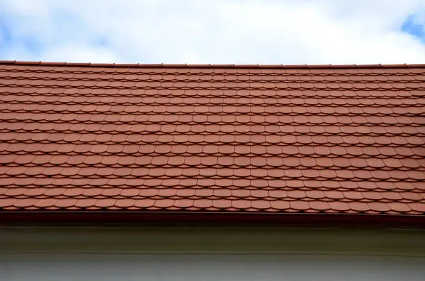 Photo of view of the roof made of red brick burnt tiles of the beaver type used in Central Europe on all historical roofs, especially in Austria. the bags overlap several times, they look like beaver teeth