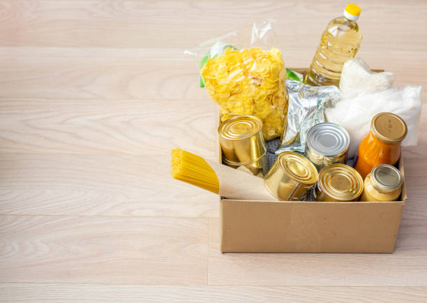 консервы, макаронные изделия и крупы картонной коробке. пожертвования на питание или концепция доставки еды. - food canned food drive motivation стоковые фото и изображения