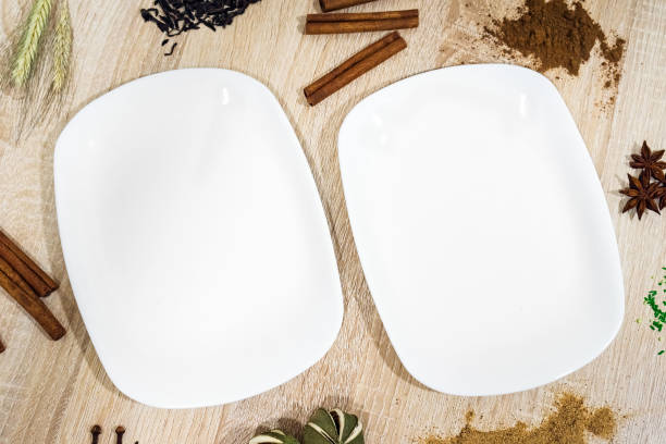 istock Two White empty plate on a light wooden table with decorative food items 1326092220