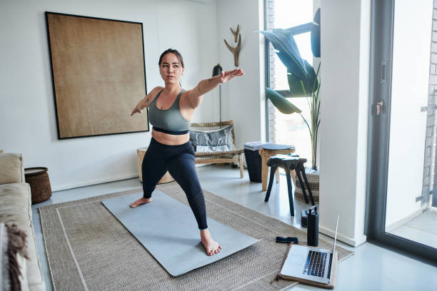 istock Shot of a young woman using a laptop while practicing her yoga routine at home 1326093237