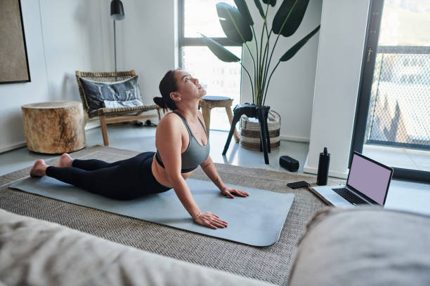 istock Shot of a young woman using a laptop while practicing her yoga routine at home 1326093255