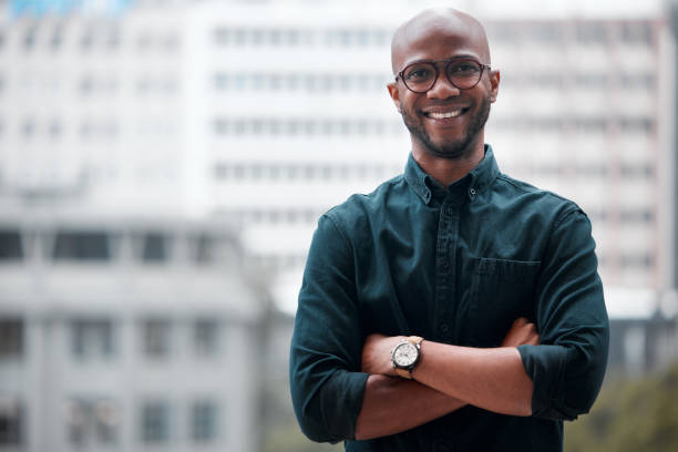 portrait of a confident young businessman standing against an urban background - looking at camera one person urban scene photography imagens e fotografias de stock