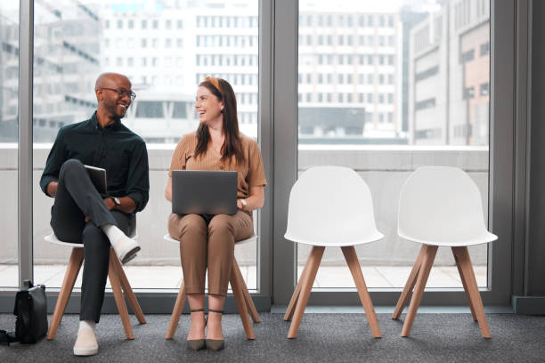 istock Shot of two businesspeople sharing a laugh while using their electronic devices against a glass background in the city 1326096370