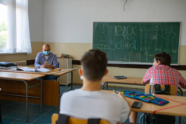 istock Teacher using a mobile phone, so he can present something to his students during their first class during school reopening 1326096856