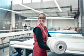 Smiling Female Textile Worker Carrying Heavy Rolled Materials For Printing Roller Machine