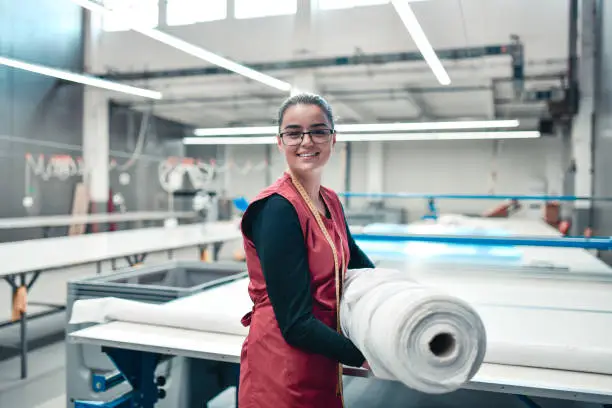 Smiling Female Textile Worker Carrying Heavy Rolled Materials For Printing Roller Machine