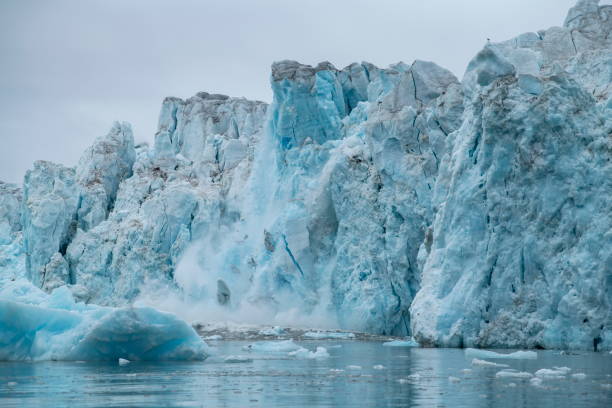 istock Series showing large chunks of ice calving from a craggy glacier, causing a large splash 1326099073