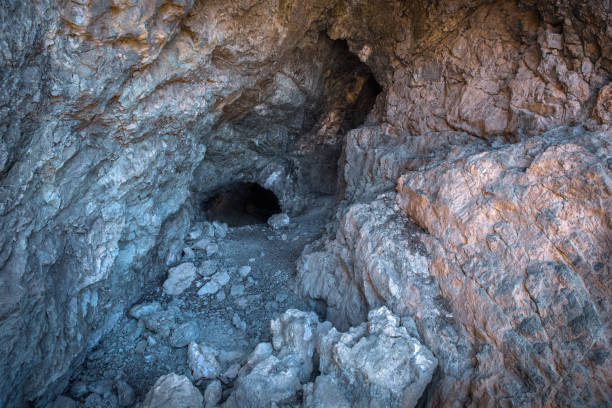 istock Cave entrance. Dark tunnel leading under a mountain 1326099381