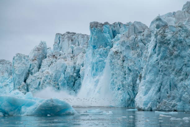 istock Series showing large chunks of ice calving from a craggy glacier, causing a large splash 1326100055