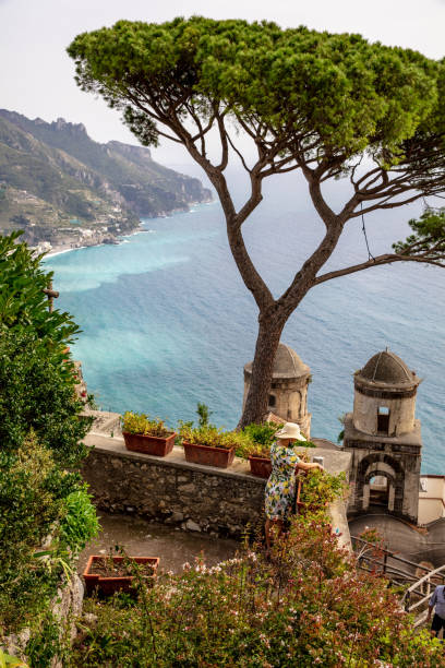 Woman In Hat Touching Plants Against Mediterranean Sea High Angle View Of Woman In Hat Touching Plants Against Mediterranean Sea Over The Church Spires In Ravello,Amalfi Coast ravello stock pictures, royalty-free photos & images