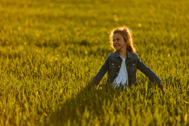 Little girl in white dress in field at sunset