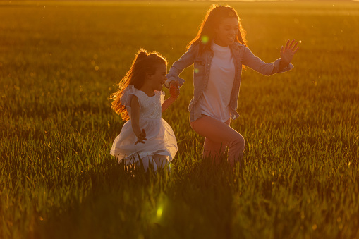 Little girl playing with mother in meadow during spring time.