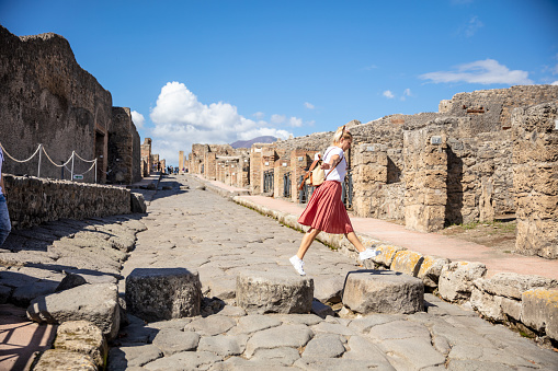 Female Tourist Jumping On Stones In Ruins Of Pompeii,Campania,Italy