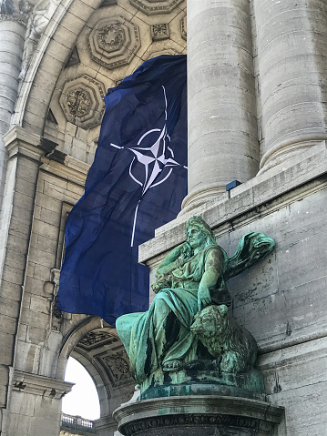 BRUSSELS, BELGIUM - JUNE 14, 2021: NATO flag fluttering in the wind in the arcades of the Cinquantenaire in Brussels