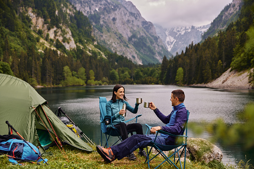 An adventurous young couple at their campsite and drinking coffee