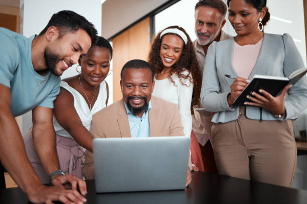 istock Shot of a group of businesspeople gathered around their manager using a laptop 1326106708
