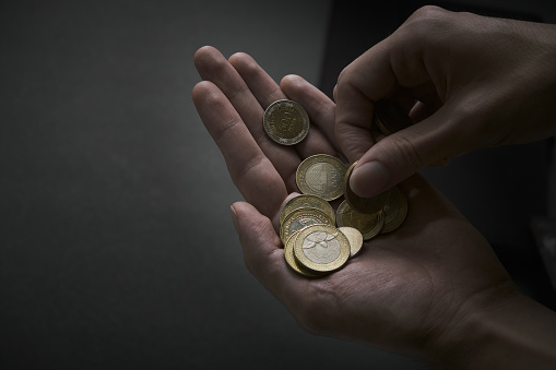 Male hands count colombian coins on a black background
