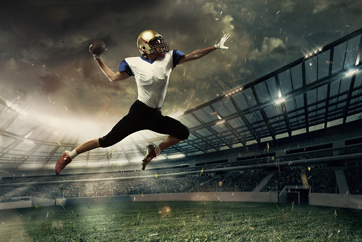 Linemen. Professional American football player in motion, action during match at stadium. Sportsman in uniform with ball jumping. Concept of movement and action, sport, lifestyle.